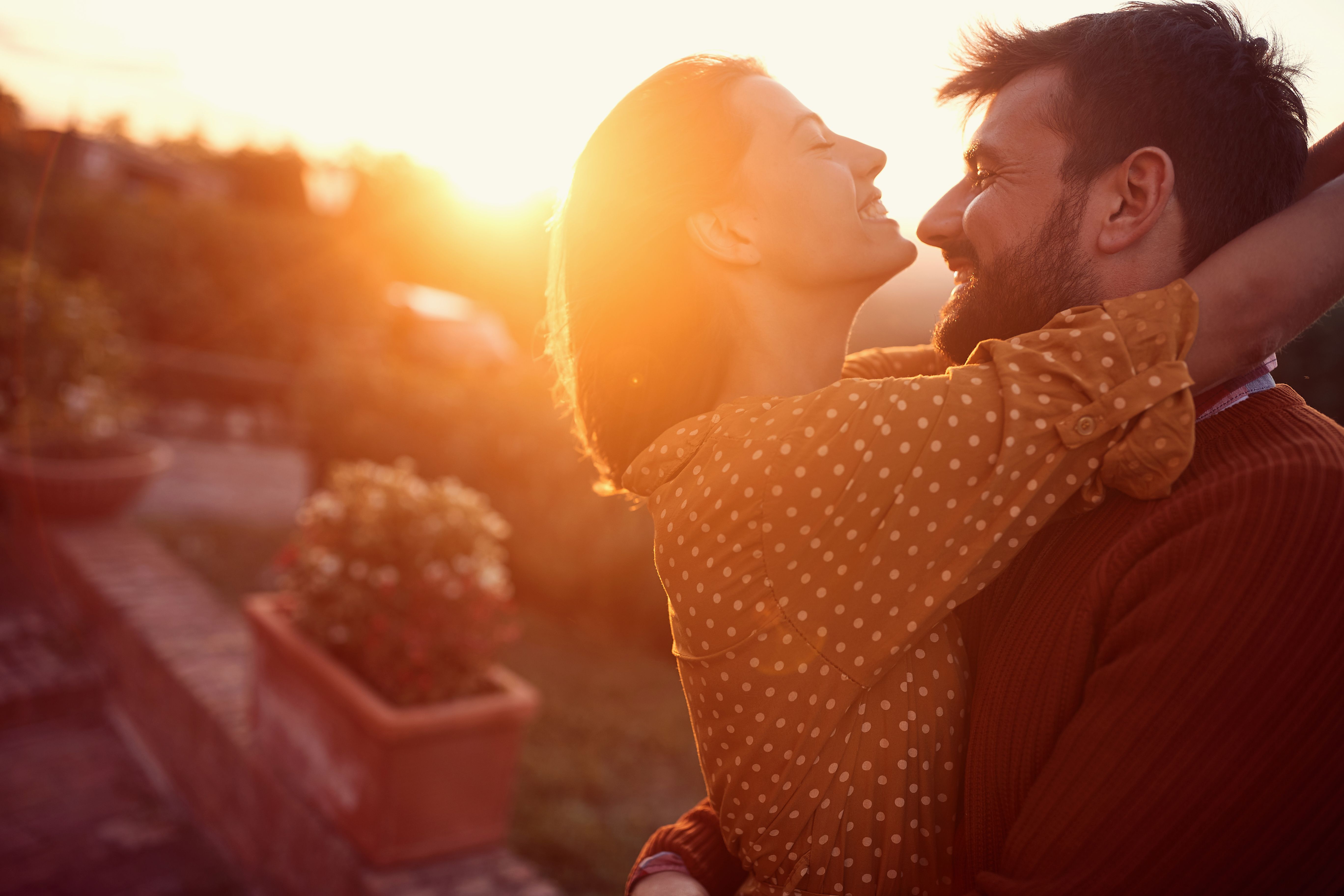 Mann und Frau umarmen sich lächelnd vor einem sonnen untergang