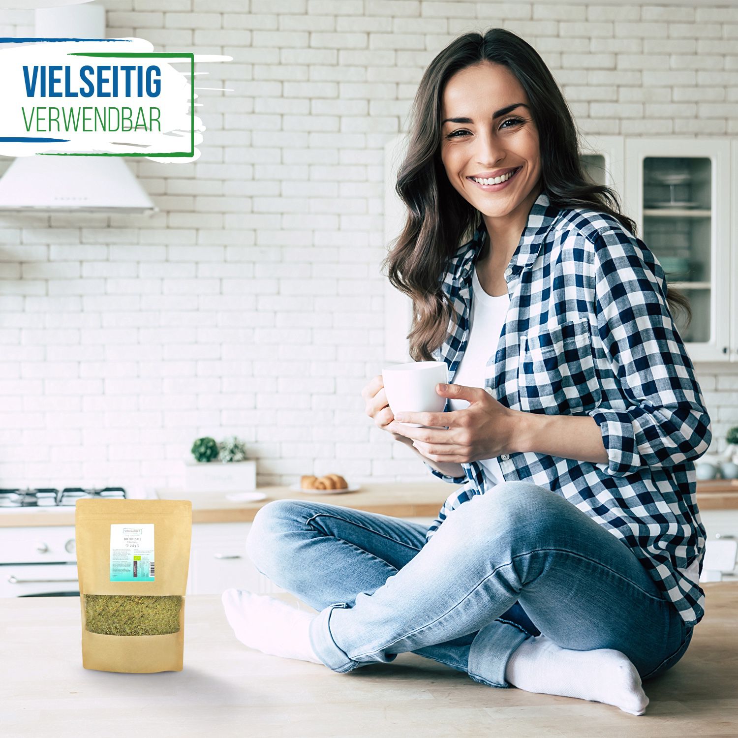 Moringa Blätter Tee Eine Frau sitzt auf einer Küchenarbeitsplatte. In der Hand hält sie eine Tasse Tee. Vor ihr ein Beutel Moringa Tee